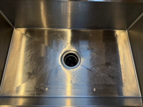 Polished stainless steel sink basin with a clean drain
